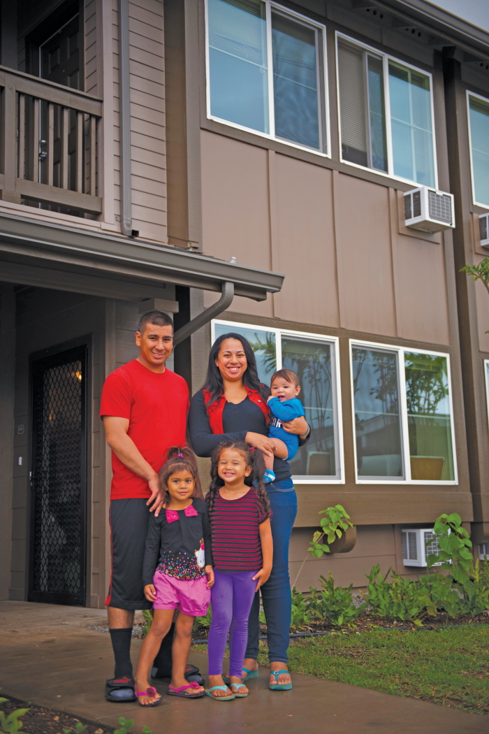 Young family smiling together in front of their new home