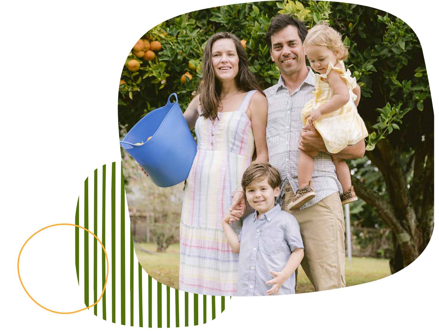 A family smiling together while standing in front of an orange orchard